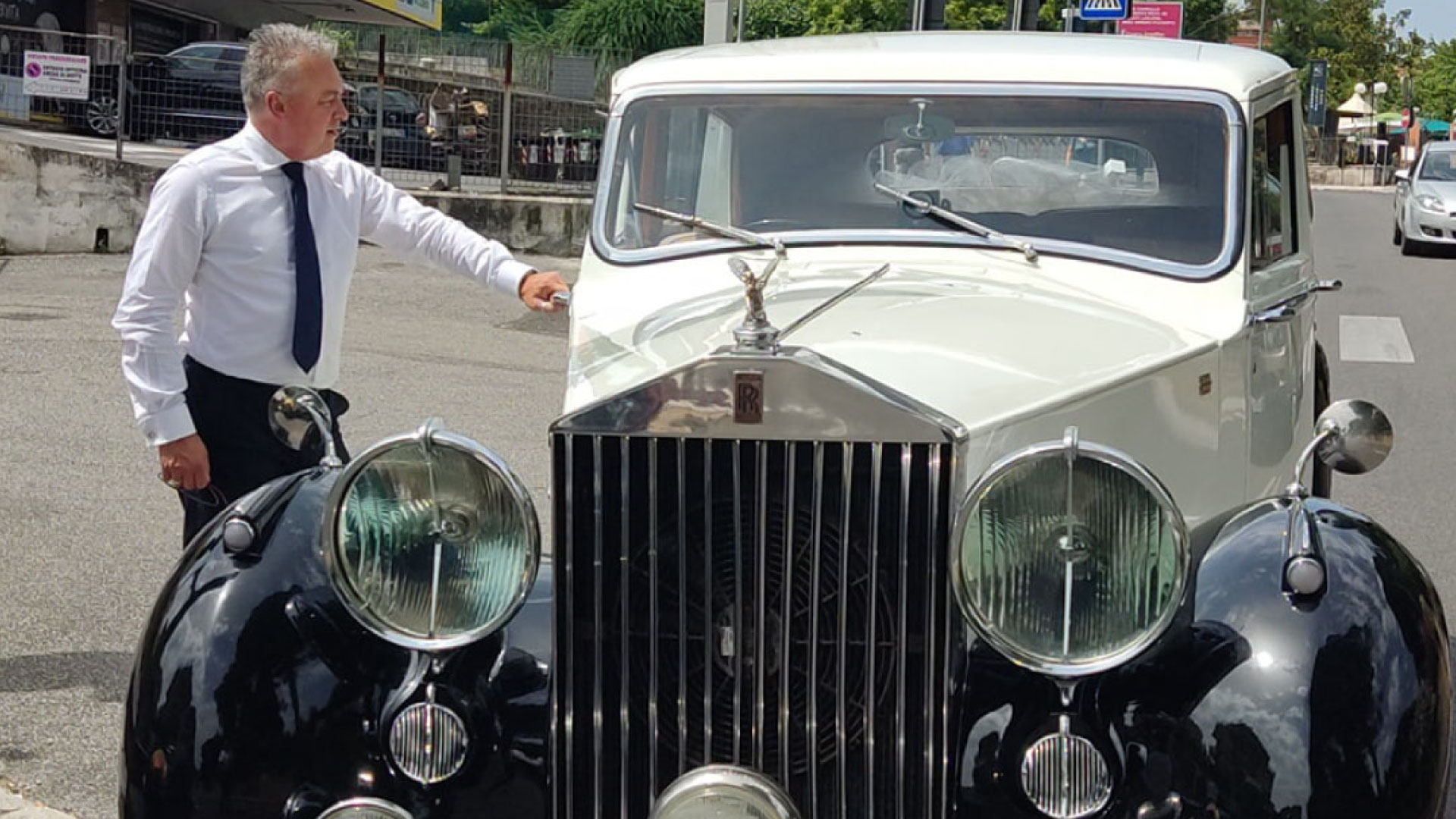 Massimiliano Dionisi, proprietario della Roman Limousine Service di Roma, che apre con eleganza la portiera di una splendida Rolls Royce d’epoca