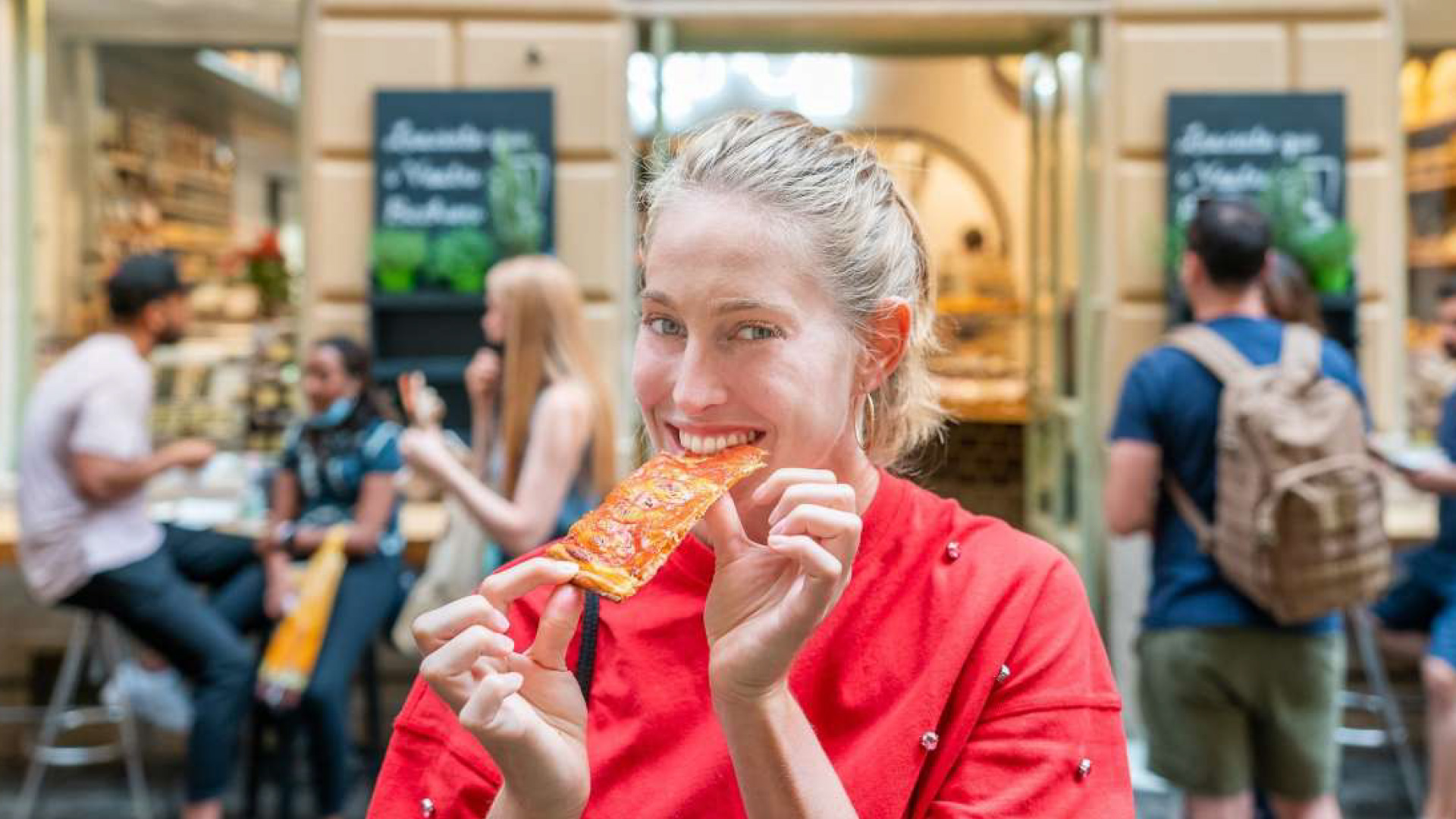 Donna che mangia un pezzo di pizza al taglio