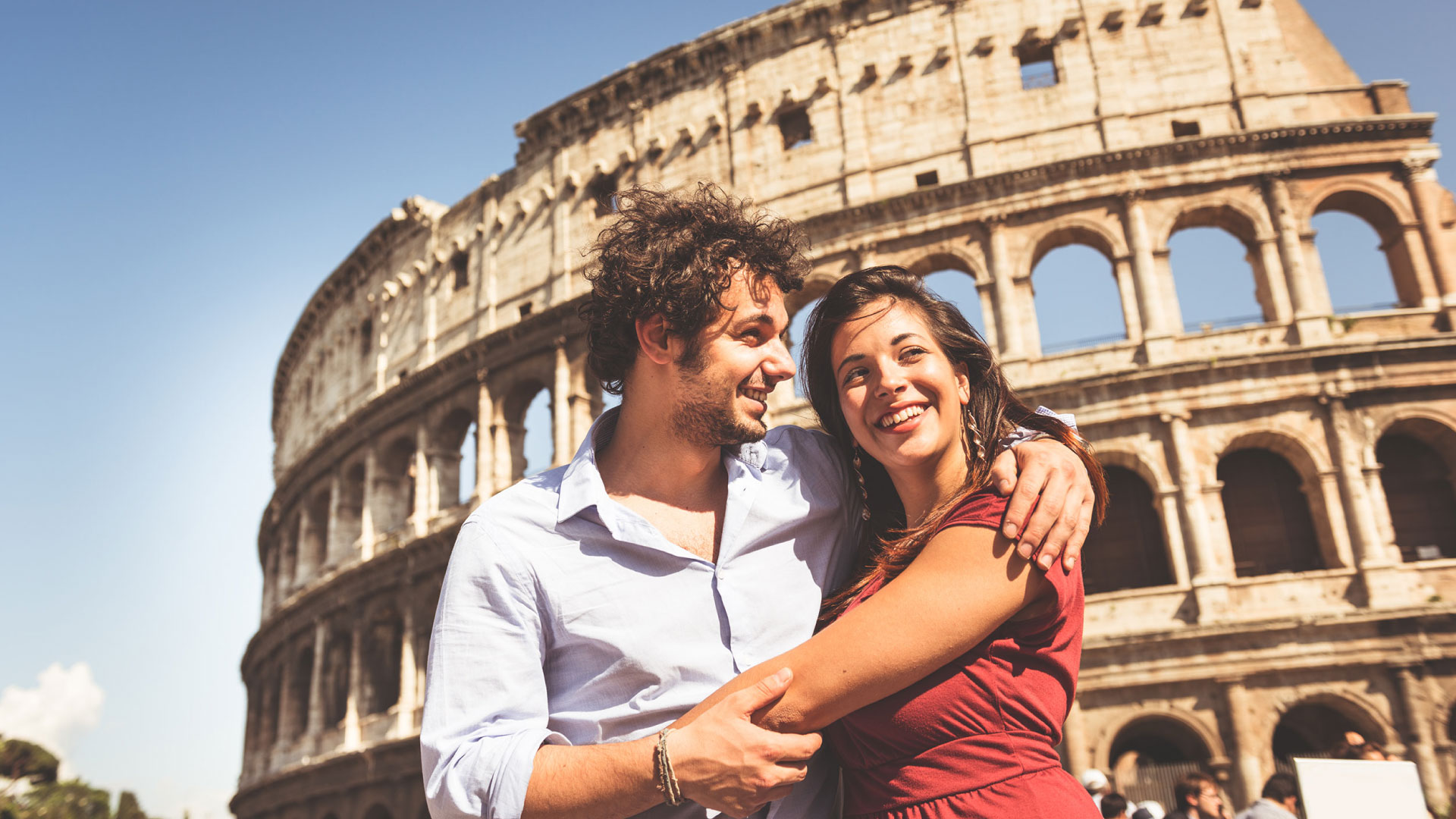Coppia innamorata davanti al Colosseo durante un viaggio a Roma in NCC con Roman Limousine Service.